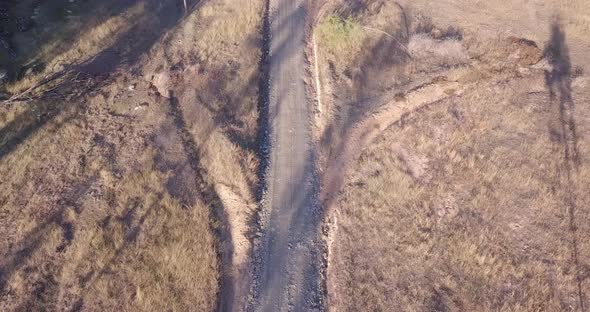 Aerial flight over a road in Australia with surrounding grassland, birds eye perspective moving forw