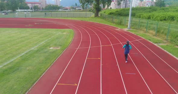 Cinematic Shot of Young Arab Sportswoman with Athletic Body in Hijab Running with Effort and