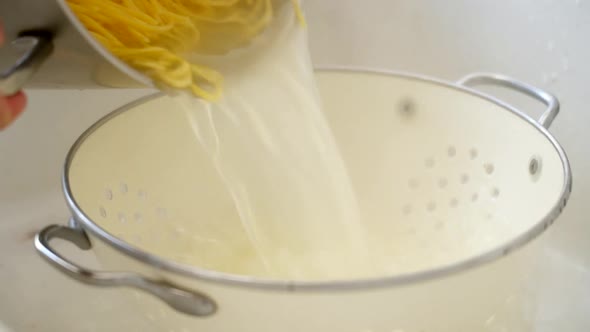 Cook pouring hot pasta into strainer