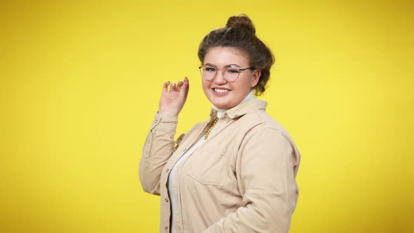 Confident Positive Plussize Woman with Bun Hairstyle in Eyeglasses Turning to Camera Smiling