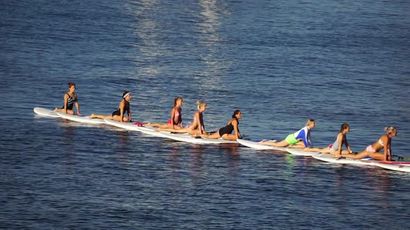 Group of Young Womens in Swimsuits Doing Yoga and Pilates on Sup Board in Calm Sea Early Morning