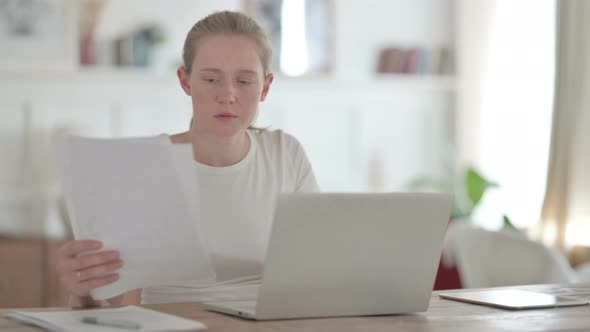 Beautiful Young Woman Reading Documents Doing Paperwork in Office