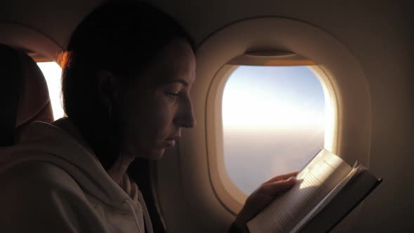 Woman Reading Book Inside Airplane