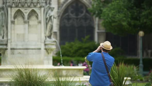 Interested Male Tourist Taking a Photo of Fountain and Notre-Dame De Paris