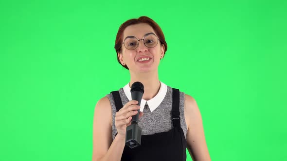 Portrait of Funny Girl in Round Glasses Is Singing Into a Microphone and Moving To the Beat of Music