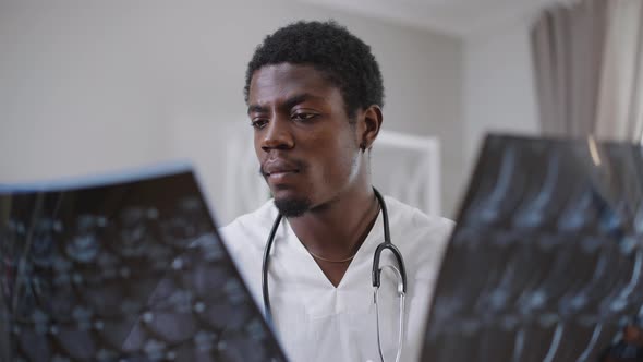 Front View Portrait African American Male Doctor Analyzing Xrays Indoors in Hospital
