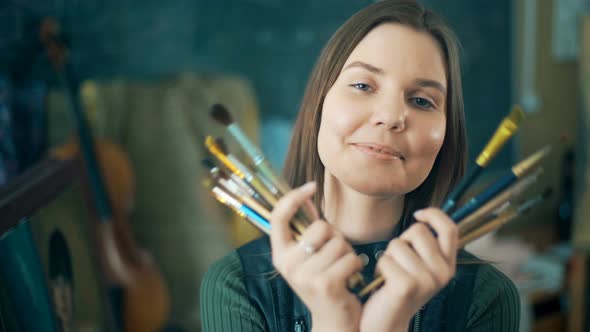 Young Smiling Women Painter with Many Brushes Looking at the Camera