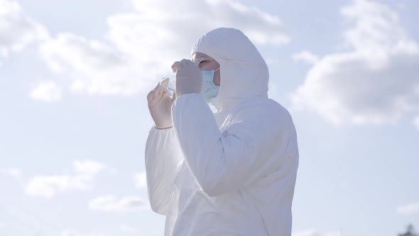 Side View of Young Caucasian Man Putting on Protective Eyeglasses at the Background of Sunny Spring