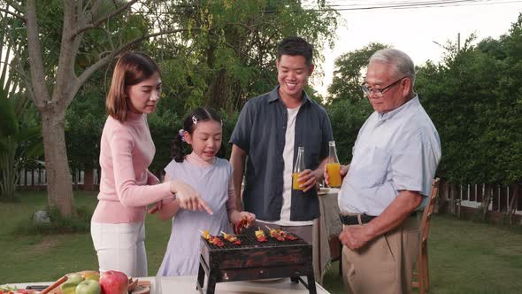 Happy Asian family having a barbecue-BBQ party together in the garden at home.