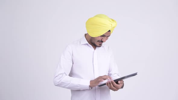Happy Bearded Indian Sikh Businessman Using Digital Tablet