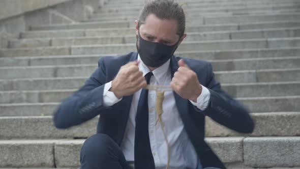 Portrait of Frustrated Businessman in Covid-19 Face Mask Checking Suicidal Rope. Young Depressed