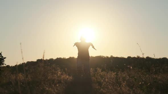 Silhouette of Young Man Running To Sunset Across Field and Jumping in 240 Fps