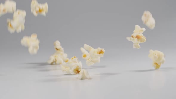 Fresh popcorn falling onto a white surface in slow motion