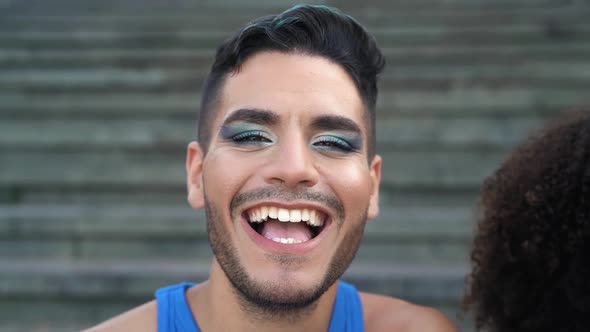 Happy gay man having fun smiling into the camera while sitting on urban stairs