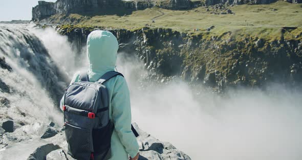 Woman Standing at the Cliff Edge Looking at Detifoss Waterfall in Iceland