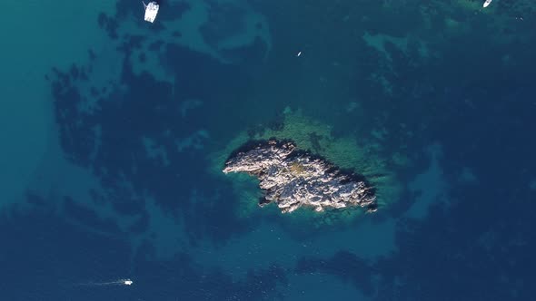 aerial view of small wild rocky island aerial top down view, coral reef around. tourist boats