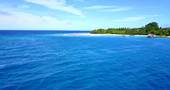 Wide flying travel shot of a white sandy paradise beach and turquoise sea background in 4K