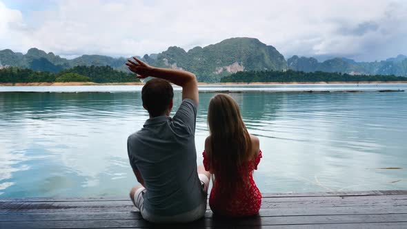 Couple on Date Sit Together on Lake Bridge and Woman Puts Head on Shoulder