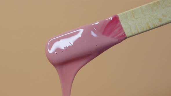 Depilatory wax master mixes heating wax with a wooden spatula. Removing unwanted hair with wax