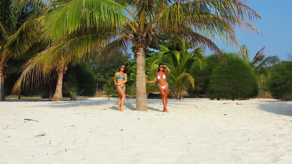 Girls sunbathing on tranquil coastline beach break by blue water with white sand background of Thail