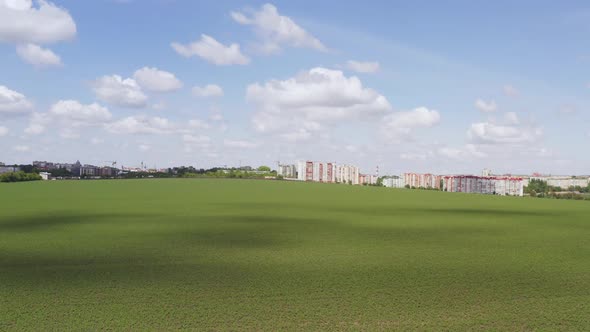 Moving Across a Green Field Approaching a Cluster of High-rise Apartment or Office Blocks at the