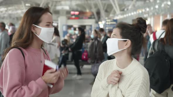 Two Women in Medical Mask Portrait Laughing and Emotionally Talking in Airport Terminal Preventing