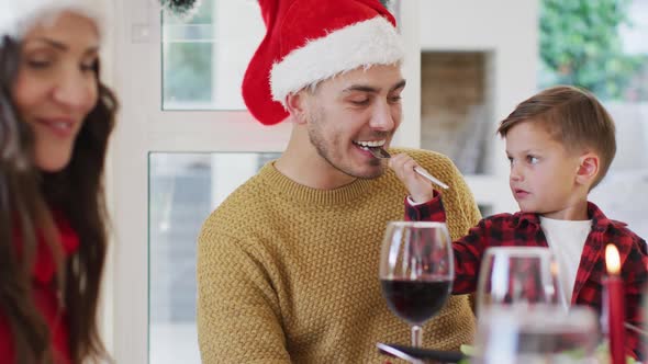 Caucasian son giving his father food with fork during christmas meal