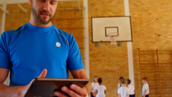 Basketball coach using digital tablet in basketball court at school 4k