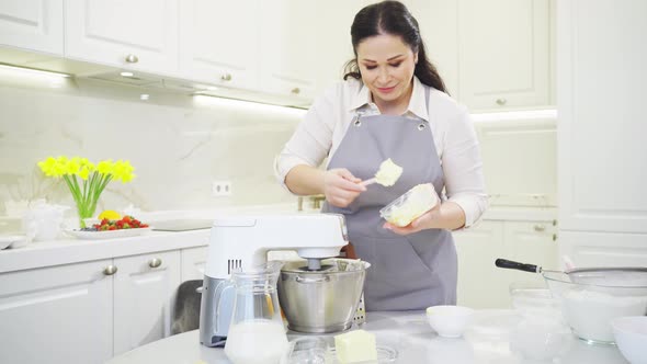 A Women Cook Adds a Butter to Prepare Dough or Cream in a Mixer Bowl