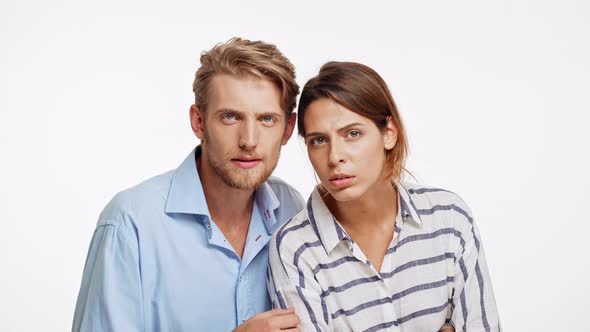 Young Caucasian Pair Looking at Camera with Suspicion on White Background