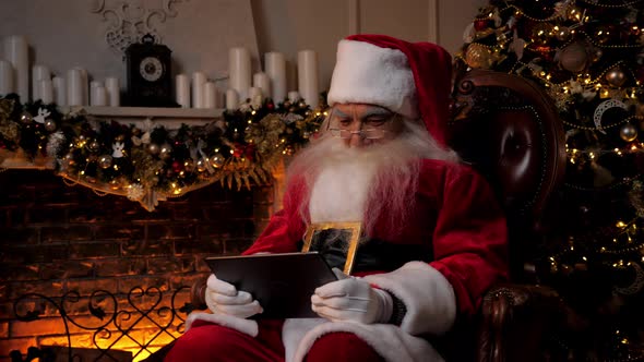 Modern Smiling Santa Claus Plays Mobile Game on Tablet New Year Winter Holidays