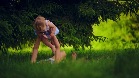 Mom with a child have fun lying in a park under a tree.