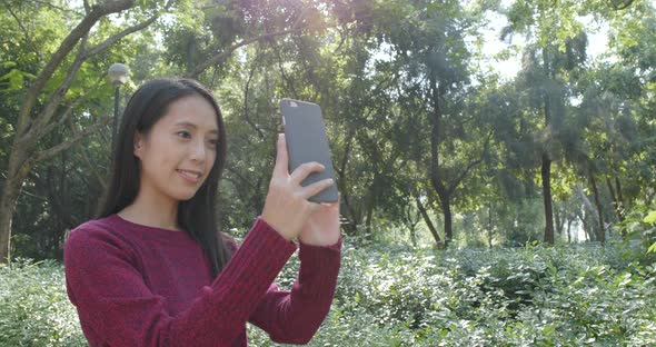 Woman taking selfie on cellphone in the park 