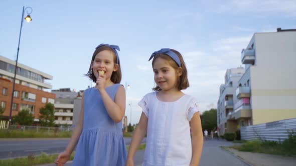 Two Cute Little Girls Walk Around the City and Eat Ice Cream