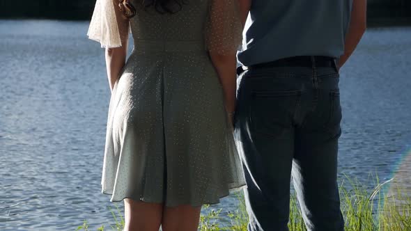 Man and Woman Holding Hands on the Background of the River