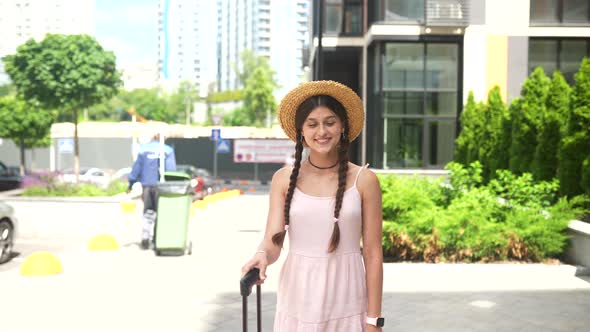 Young Woman Walks with a Suitcase on the Street