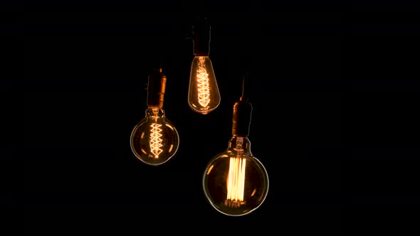Three Different Shape Retro Light Bulbs on Black Background. Three Vintage Lights Swing in the Dark