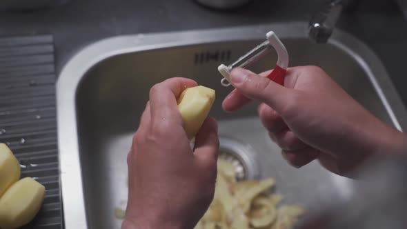A Man Peels Potatoes with a Special Vegetable Peeler