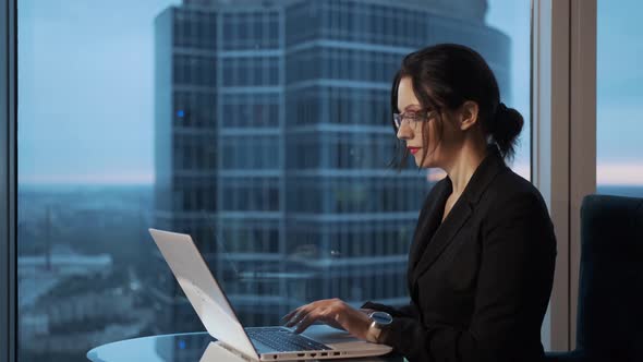 Young Woman Working on Laptop Sitting By the Window in the Office