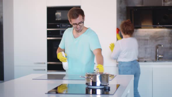 Young Couple in Casual Clothes Cleaning Kitchen Together.