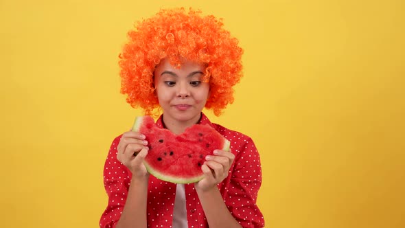 Happy Hungry Teen Girl in Orange Hair Wig Showing Tongue and Biting Water Melon Slice Summer