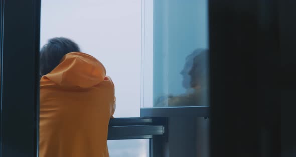 Young man looking out of window to foggy view
