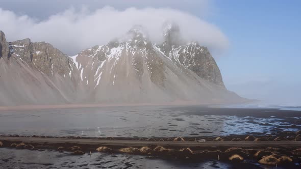 Drone Shot Of Car Driving Along Narrow Track With Sea And Mountain