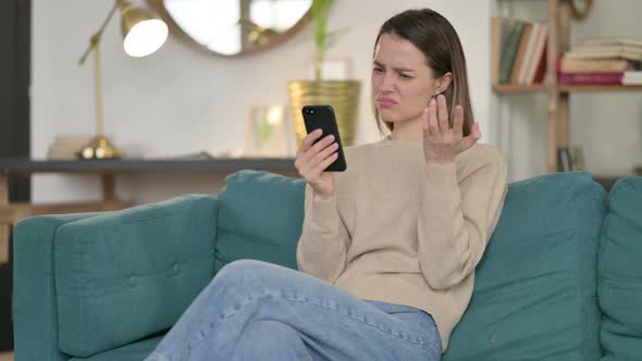 Young Woman Reacting To Loss on Smartphone on Sofa 