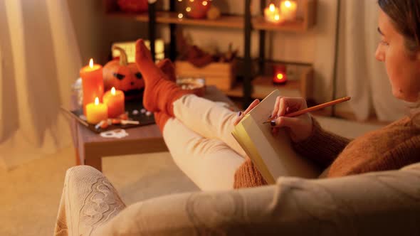 Woman Writing To Diary at Home on Halloween