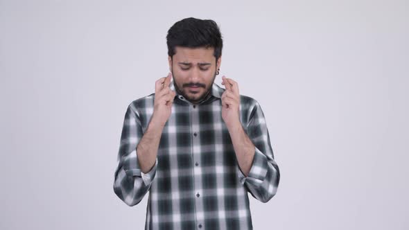 Portrait of Young Bearded Indian Man Wishing with Fingers Crossed