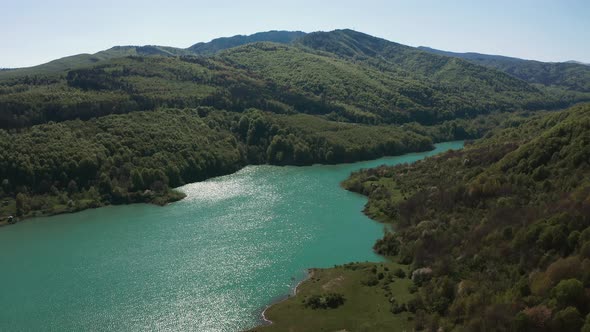 Sunlight glistens off surface of Maneciu Dam Lake in Romania. Aerial flyover