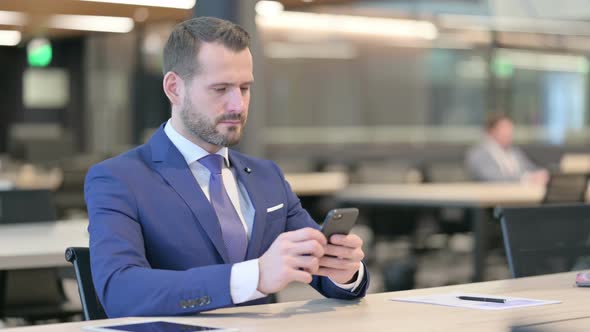 Middle Aged Businessman Using Smartphone at Work