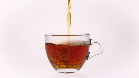 Black Tea Being Poured in Glass Cup on White Background