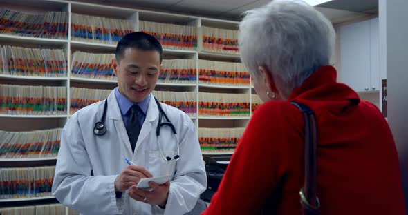 Young Asian male doctor prescribing medicines for patient in clinic 4k